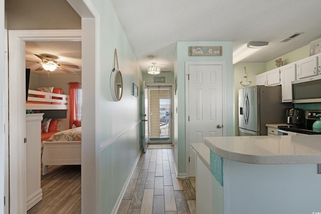 kitchen featuring visible vents, a textured ceiling, appliances with stainless steel finishes, and light wood finished floors