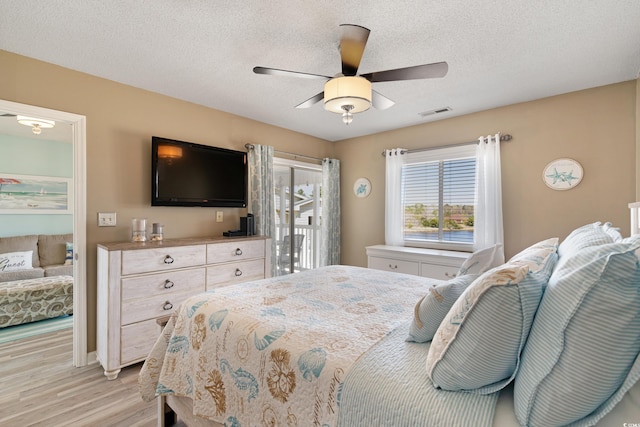 bedroom with a ceiling fan, visible vents, light wood-style flooring, a textured ceiling, and access to outside