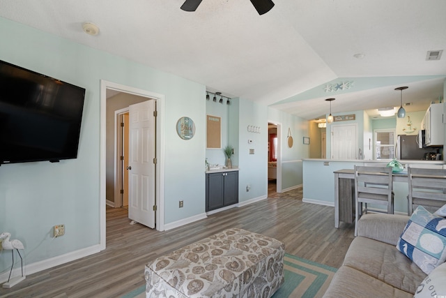 living room featuring visible vents, wood finished floors, baseboards, ceiling fan, and vaulted ceiling