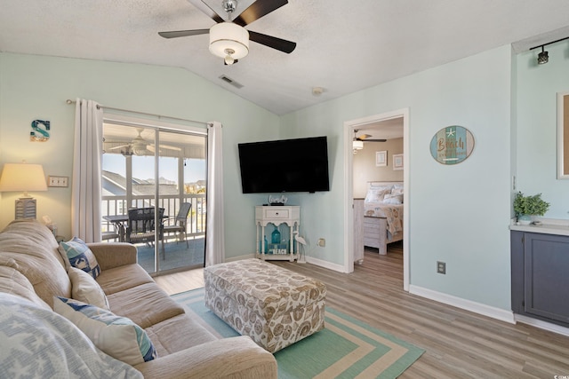 living area with baseboards, visible vents, light wood-style flooring, ceiling fan, and vaulted ceiling