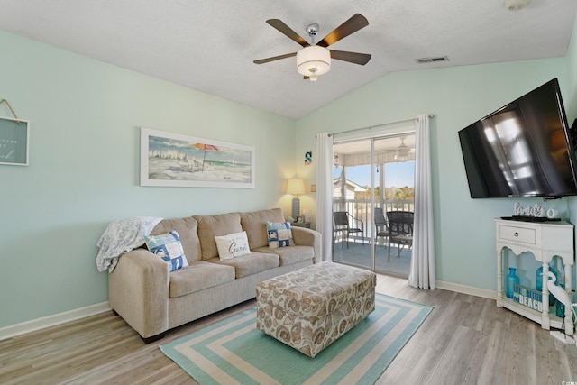 living area featuring vaulted ceiling, visible vents, a ceiling fan, and wood finished floors