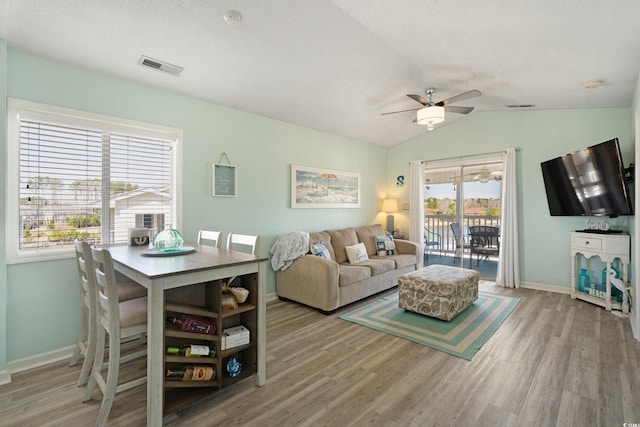 living area featuring wood finished floors, a ceiling fan, visible vents, and vaulted ceiling