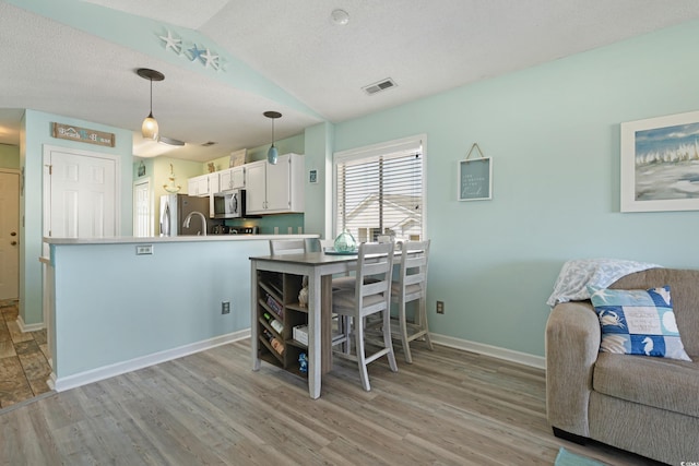 kitchen featuring white cabinetry, vaulted ceiling, light wood-type flooring, and appliances with stainless steel finishes