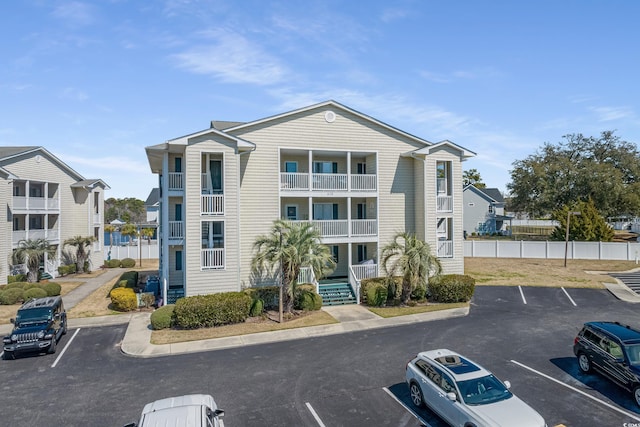 view of building exterior featuring a residential view, uncovered parking, and fence