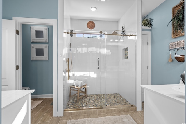 bathroom with wood finish floors, a stall shower, and vanity