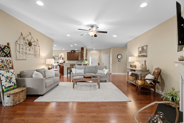 living area with wood finished floors, recessed lighting, arched walkways, baseboards, and ceiling fan