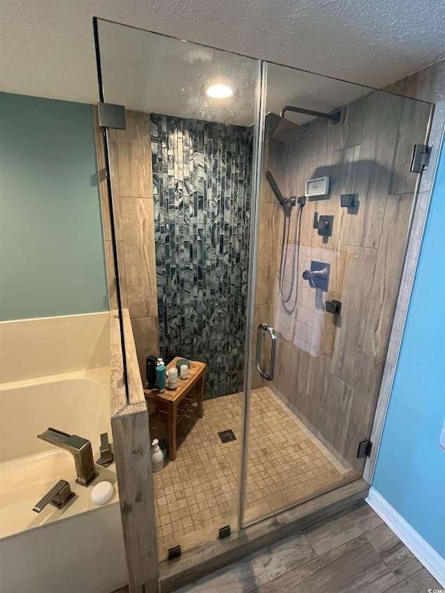 full bathroom with a textured ceiling, a stall shower, and a bath