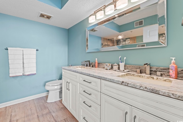 bathroom featuring a sink, visible vents, toilet, and wood finished floors