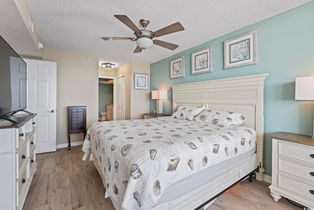 bedroom with a closet, a textured ceiling, baseboards, and wood finished floors