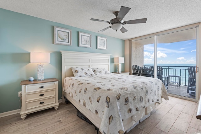 bedroom with access to outside, a textured ceiling, floor to ceiling windows, light wood-style floors, and baseboards