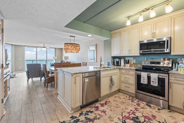 kitchen featuring a sink, cream cabinets, appliances with stainless steel finishes, and a peninsula