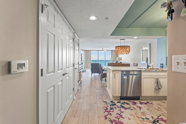 kitchen featuring a sink, stainless steel dishwasher, open floor plan, light wood-style floors, and a wall of windows