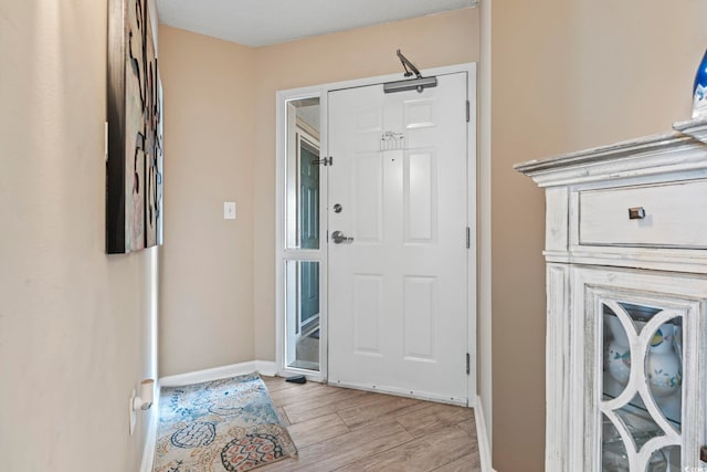 foyer entrance with light wood finished floors and baseboards