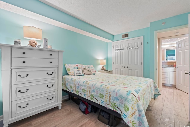 bedroom featuring a closet, visible vents, light wood-style flooring, and a textured ceiling