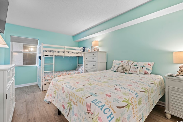 bedroom featuring wood finished floors, baseboards, and a textured ceiling