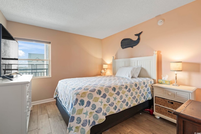 bedroom with baseboards, light wood finished floors, and a textured ceiling