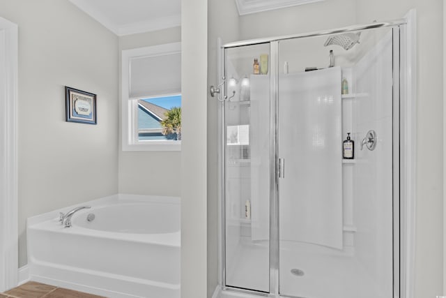 bathroom featuring a stall shower, ornamental molding, a bath, and baseboards
