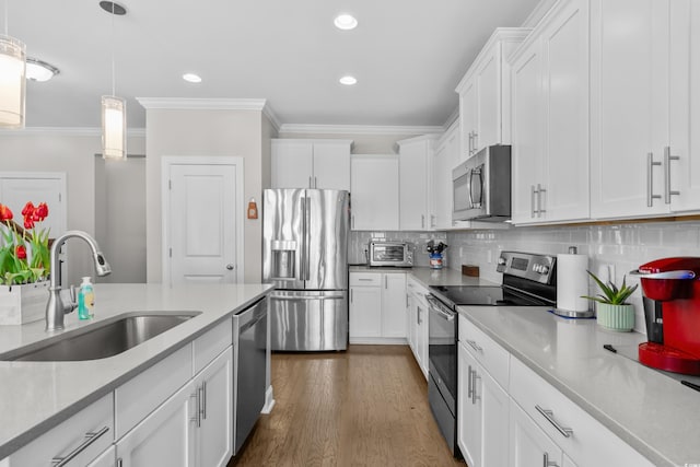 kitchen featuring appliances with stainless steel finishes, a sink, ornamental molding, white cabinets, and backsplash