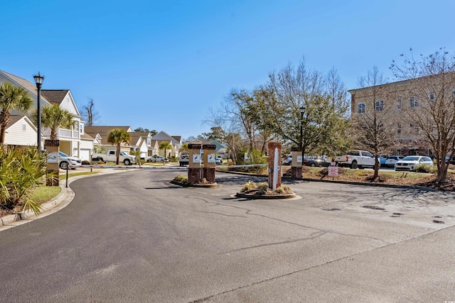 view of asphalt road with street lights, a residential view, and curbs