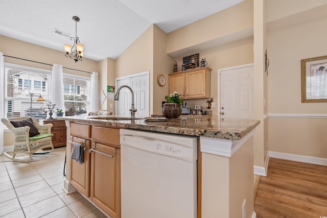 kitchen featuring visible vents, a center island with sink, light brown cabinets, white dishwasher, and vaulted ceiling