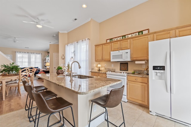 kitchen featuring white appliances, a breakfast bar area, ceiling fan, and a sink