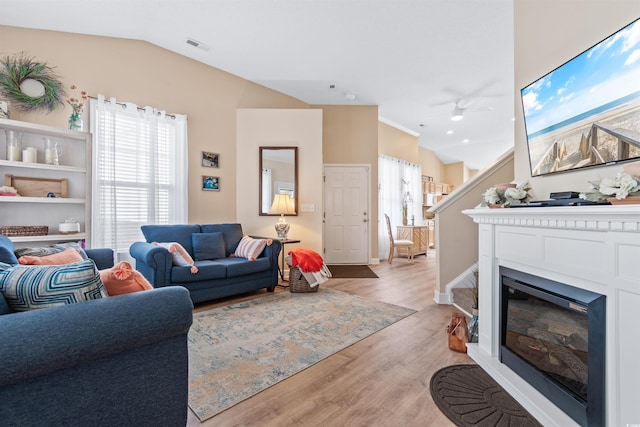 living room featuring visible vents, lofted ceiling, light wood-style floors, and a ceiling fan