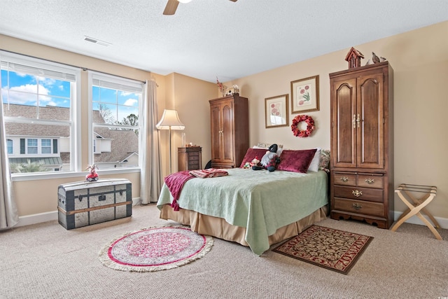 bedroom featuring light carpet, baseboards, visible vents, and a textured ceiling