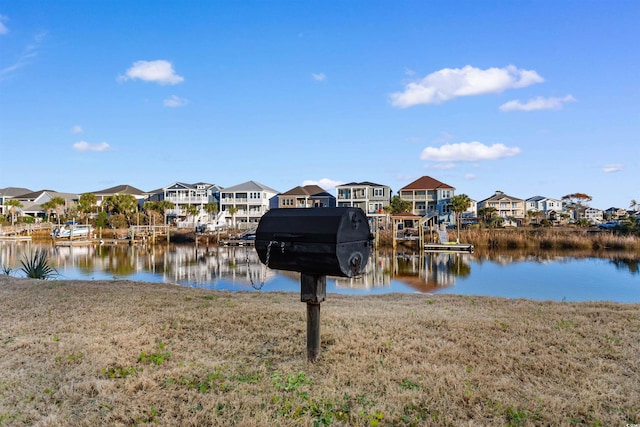 dock area with a residential view, a yard, and a water view