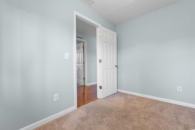 unfurnished room with baseboards, carpet floors, and a textured ceiling