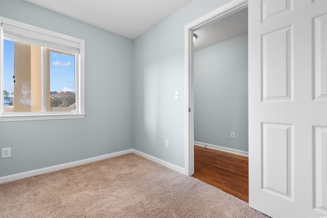 unfurnished bedroom featuring a textured ceiling, baseboards, and carpet floors