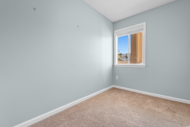 carpeted spare room featuring baseboards and a textured ceiling