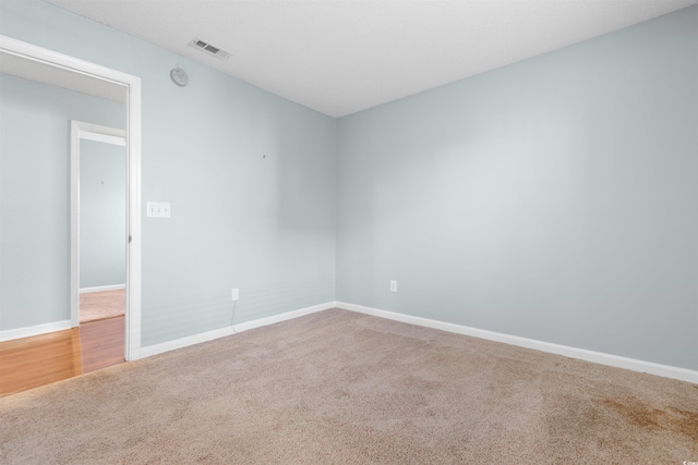 empty room with visible vents, baseboards, and carpet