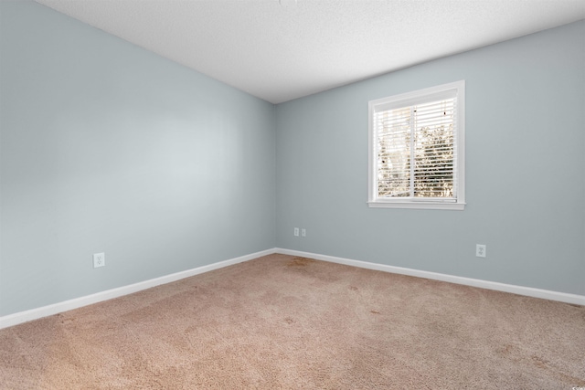 carpeted empty room featuring a textured ceiling and baseboards