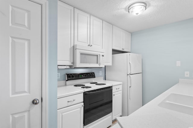 kitchen featuring white appliances, a sink, light countertops, a textured ceiling, and white cabinetry