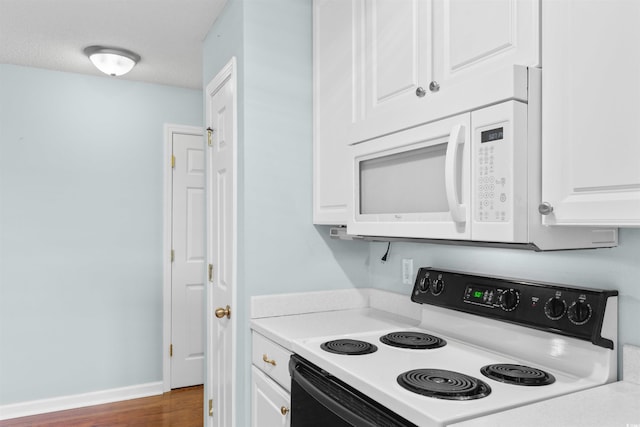 kitchen featuring light countertops, white cabinets, white microwave, and range with electric cooktop