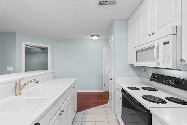 kitchen featuring white microwave, range with electric stovetop, light countertops, and a sink