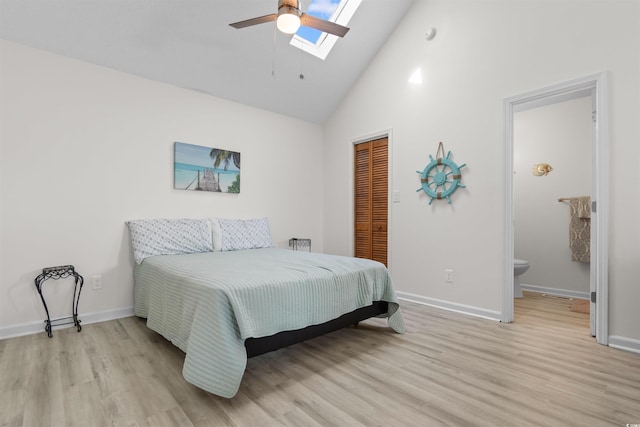 bedroom with a closet, light wood-style floors, baseboards, high vaulted ceiling, and a skylight