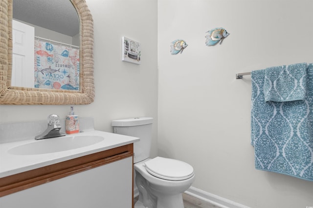 full bathroom with vanity, baseboards, wood finished floors, and toilet