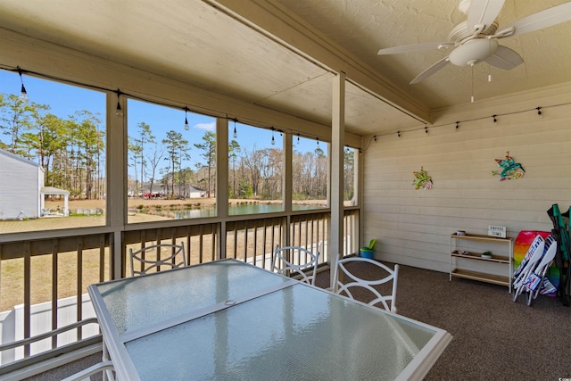 sunroom / solarium featuring outdoor dining area, a water view, a ceiling fan, and a healthy amount of sunlight
