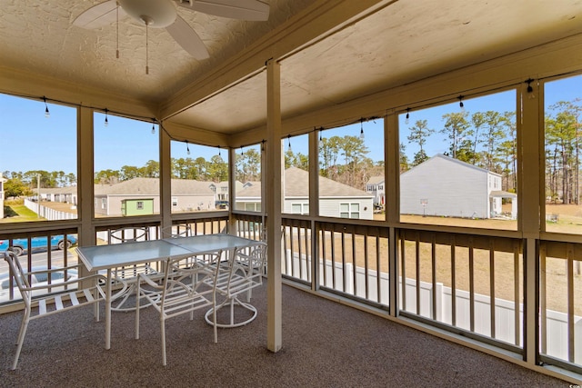 sunroom featuring a ceiling fan and a residential view