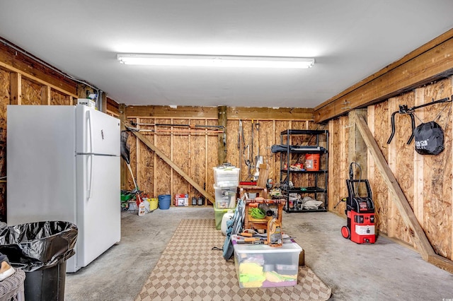 below grade area with wooden walls and freestanding refrigerator