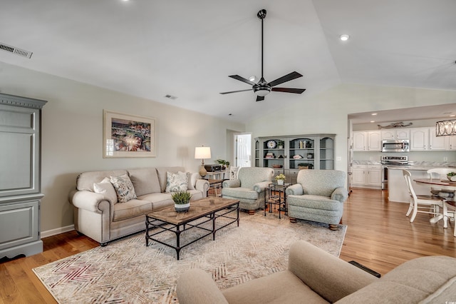 living area with visible vents, light wood-style floors, a ceiling fan, and vaulted ceiling