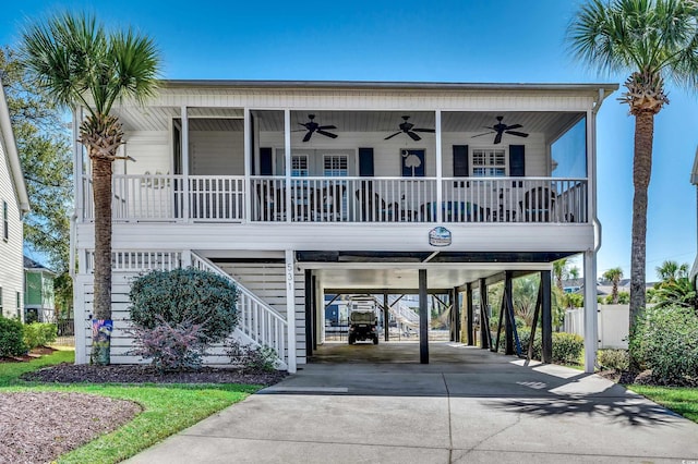 coastal inspired home featuring a carport, a porch, stairs, and a ceiling fan