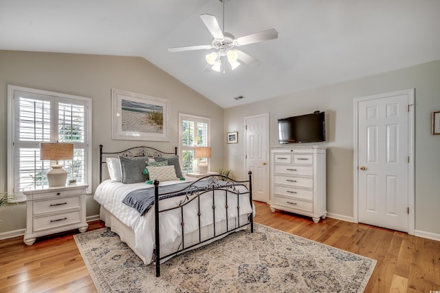 bedroom featuring visible vents, light wood-type flooring, baseboards, and vaulted ceiling