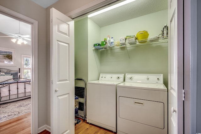 washroom featuring washer and dryer, a textured ceiling, light wood finished floors, ceiling fan, and laundry area