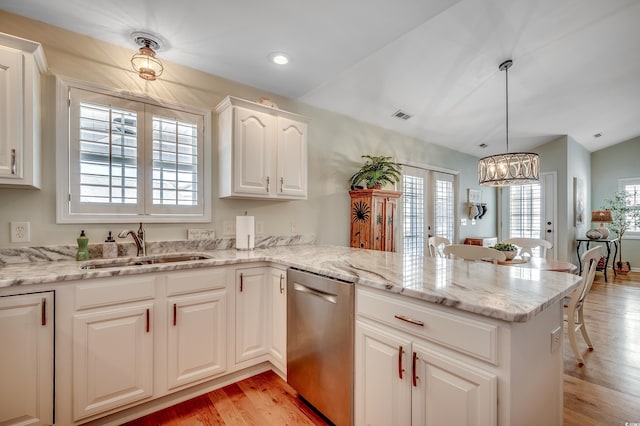 kitchen with light wood finished floors, a peninsula, an inviting chandelier, a sink, and dishwasher