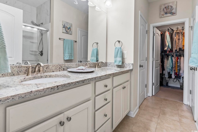 bathroom featuring tile patterned flooring, a stall shower, double vanity, and a sink