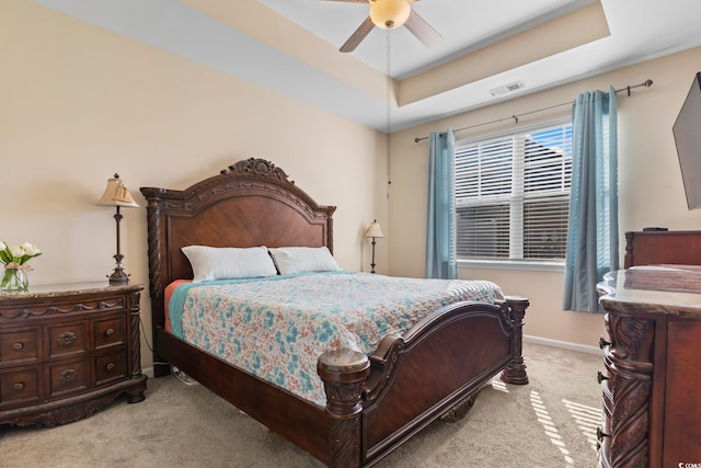 bedroom featuring a ceiling fan, baseboards, visible vents, light carpet, and a raised ceiling