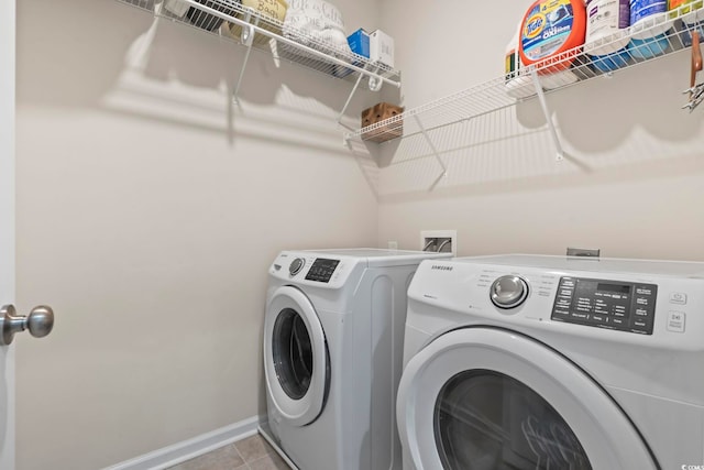 washroom featuring laundry area, light tile patterned floors, baseboards, and washing machine and clothes dryer