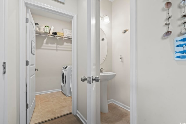 bathroom with washer and dryer, a walk in closet, and baseboards